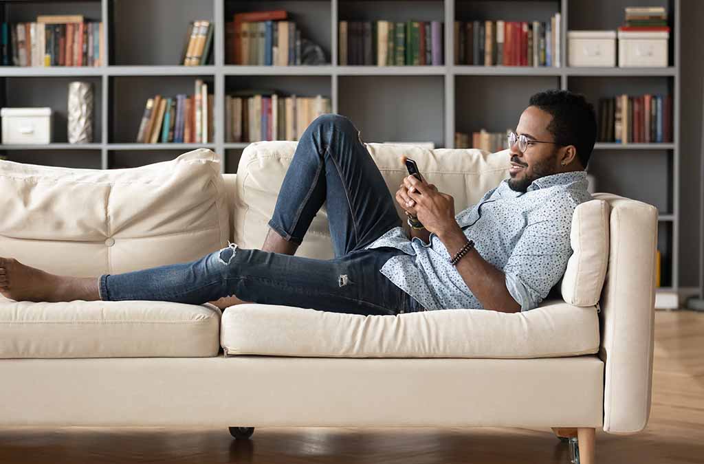 A man lying on the couch looking at his phone